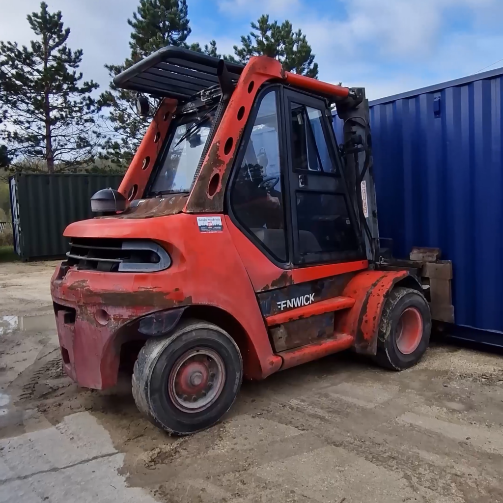 Chariot élévateur porte-conteneur saisissant un conteneur à l'extérieur de l'atelier