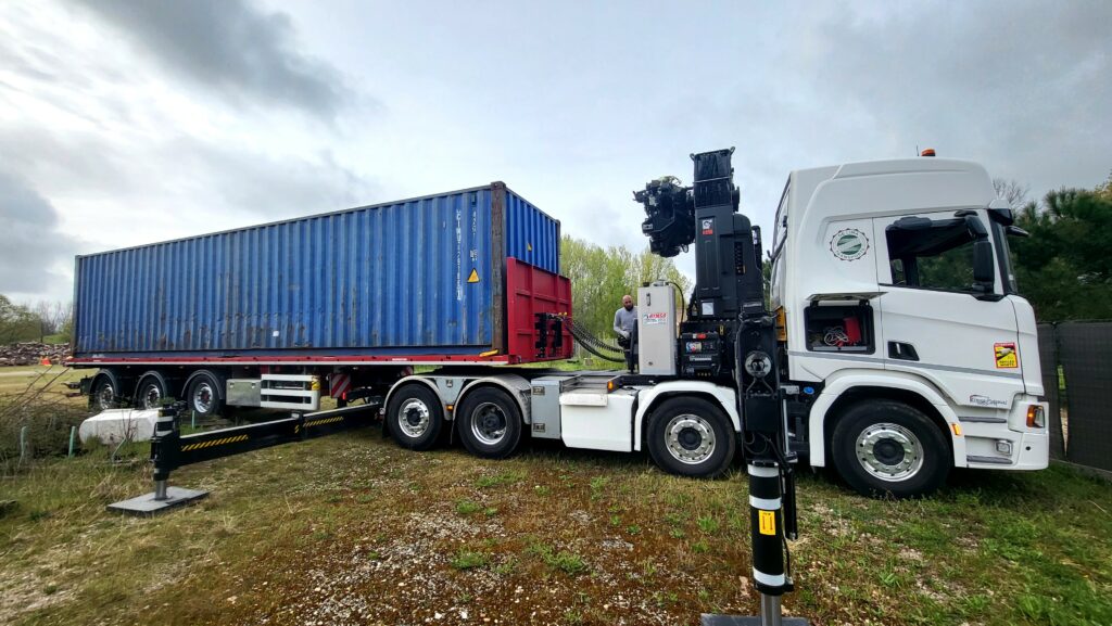 Container 40 pieds d'occasion sur un camion-grue, prêt à être déchargé.