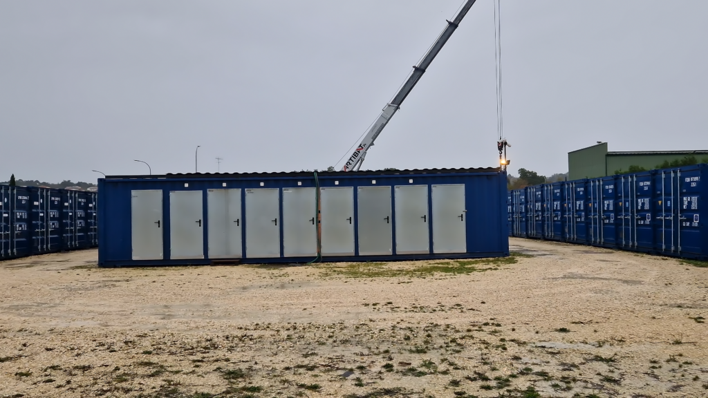 Grue mobile installant un container de stockage bleu parmi une rangée de containers similaires chez Selfstock à Boulazac.