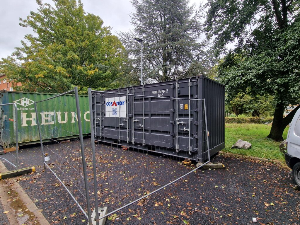 Container de stockage gris 20 pieds pour Cosanor sur un chantier à Roubaix, sécurisé par une clôture.