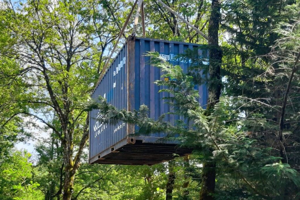 Container de stockage suspendu par grue entre les arbres lors de la livraison à Saint-Rabier