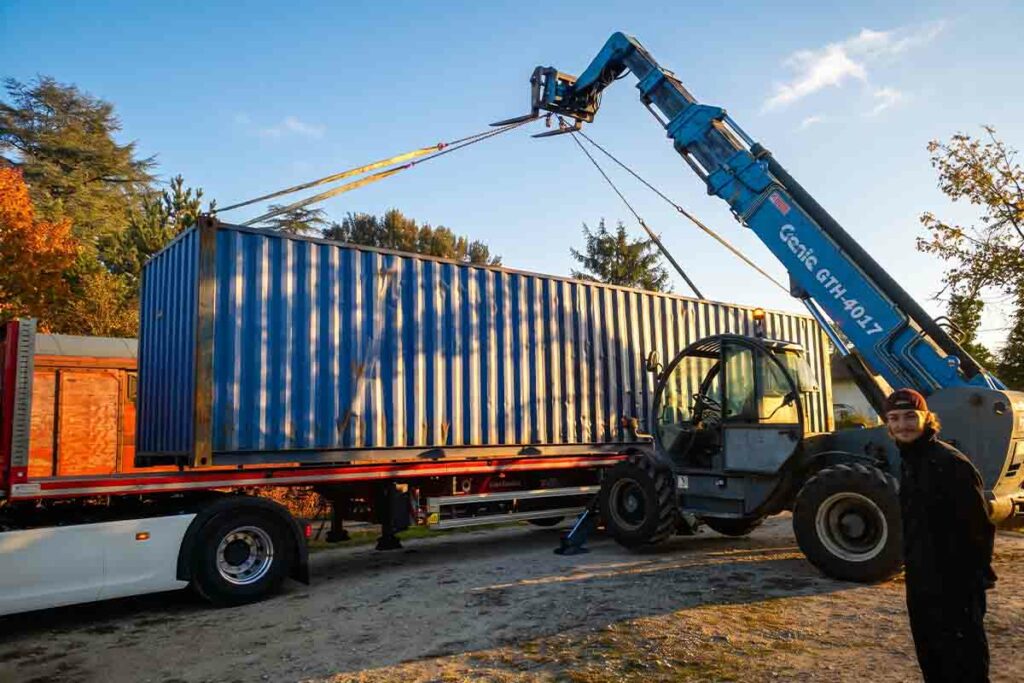 Chariot télescopique déchargeant un container 40 pieds d'occasion depuis un semi-remorque à Martel