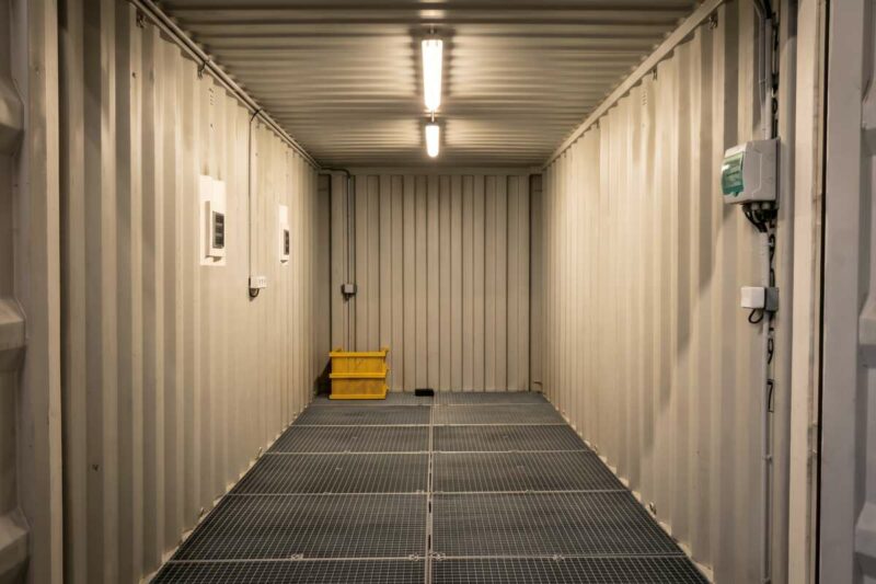 Intérieur d'un container industriel aménagé pour Kyocera, avec sol caillebotis et station de nettoyage Karcher intégrée