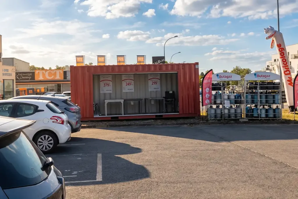 Container 20 pieds rouge Mr. Bricolage ouvert en point de vente, exposant des salons de jardin devant le magasin à Boulazac (24)