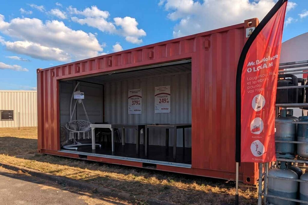 Façade latérale du container ouverte, rideau métallique relevé, salons de jardin et fauteuil suspendu exposés à Boulazac (24)
