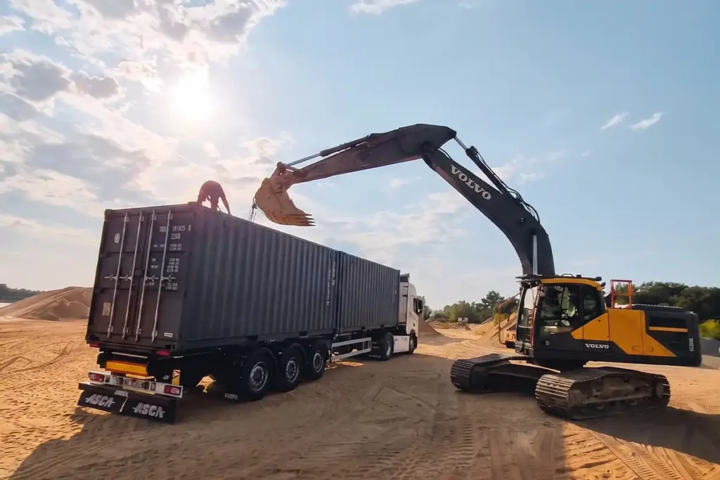 Deux containers 20 pieds sur porte-conteneurs et pelle Volvo dans une carrière de sable à Saint-Sornin (17)