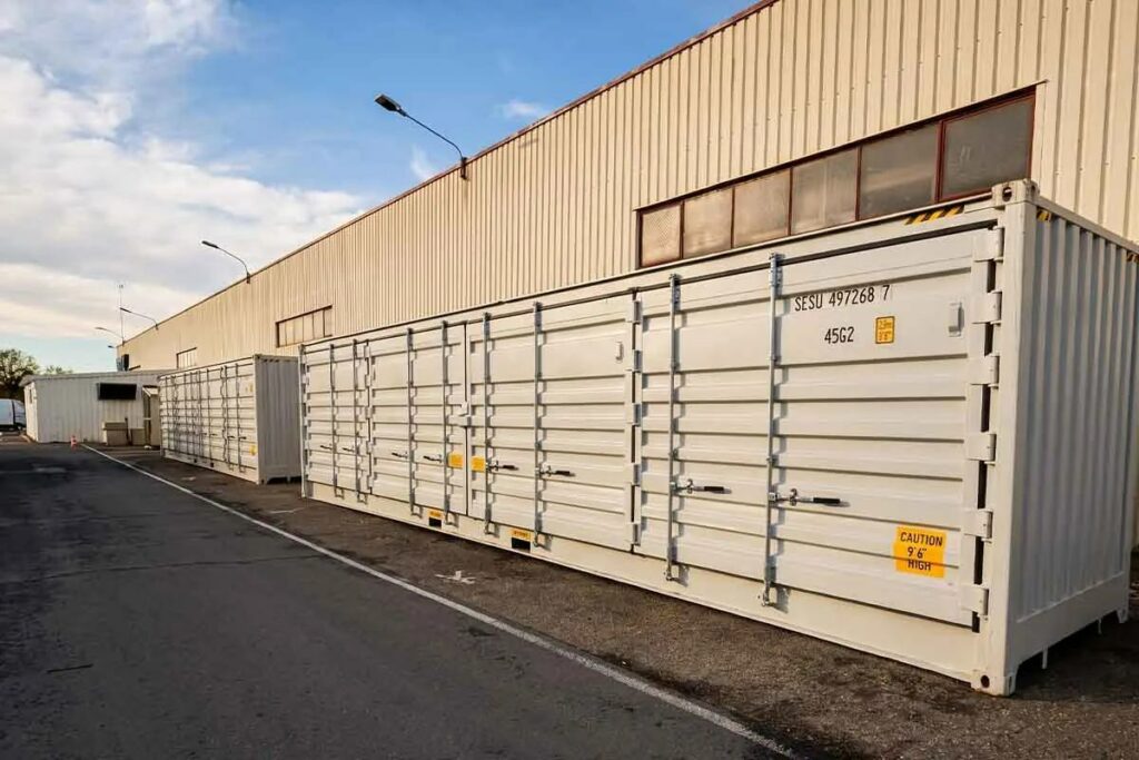Deux containers 40 pieds open side gris clair posés le long de l'entrepôt Smurfit Westrock à Saint-Seurin-sur-l'Isle