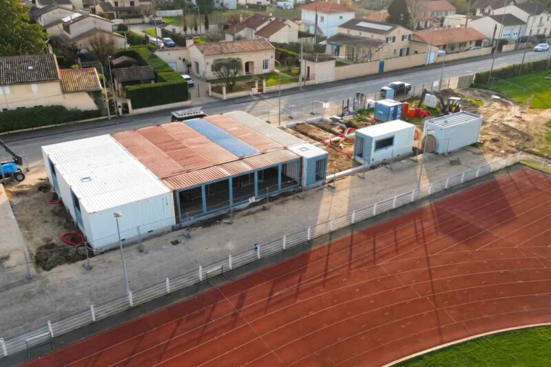 Ensemble de containers formant la Maison du Rugby de Libourne, en bordure de piste d'athlétisme, en Gironde