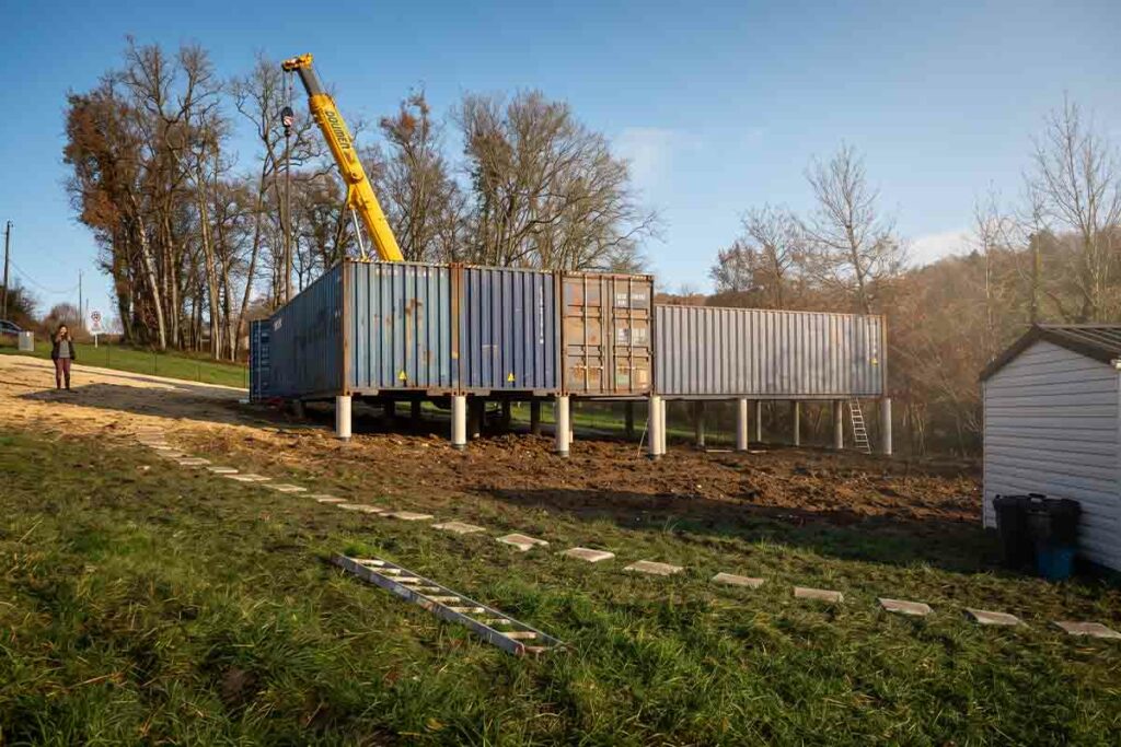 Grue automotrice déchargeant un container 40 pieds High Cube sur ses plots béton à Chantérac