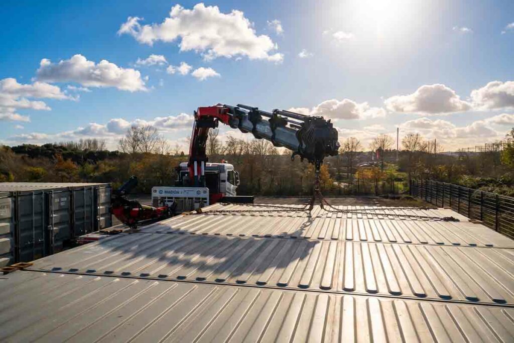 Camion-grue et chaînes d'élingage lors de la pose des containers d'un parc de self-stockage