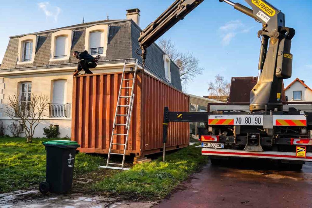 Grutage d'un container 20 pieds d'occasion au-dessus d'une pelouse à Savigny-sur-Orge (91)