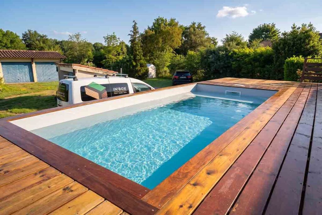 Bassin de piscine container rempli à Neuvic, plage immergée au premier plan et margelles en bois exotique