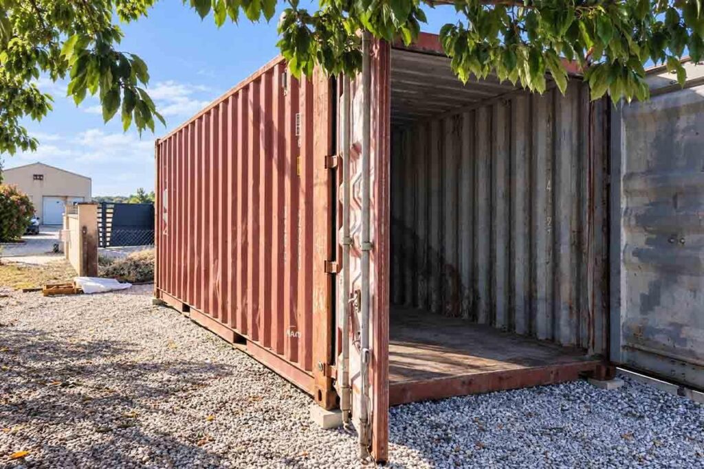 Container de stockage 20 pieds posé sur plots béton dans un jardin de Gimeux, les deux portes ouvertes